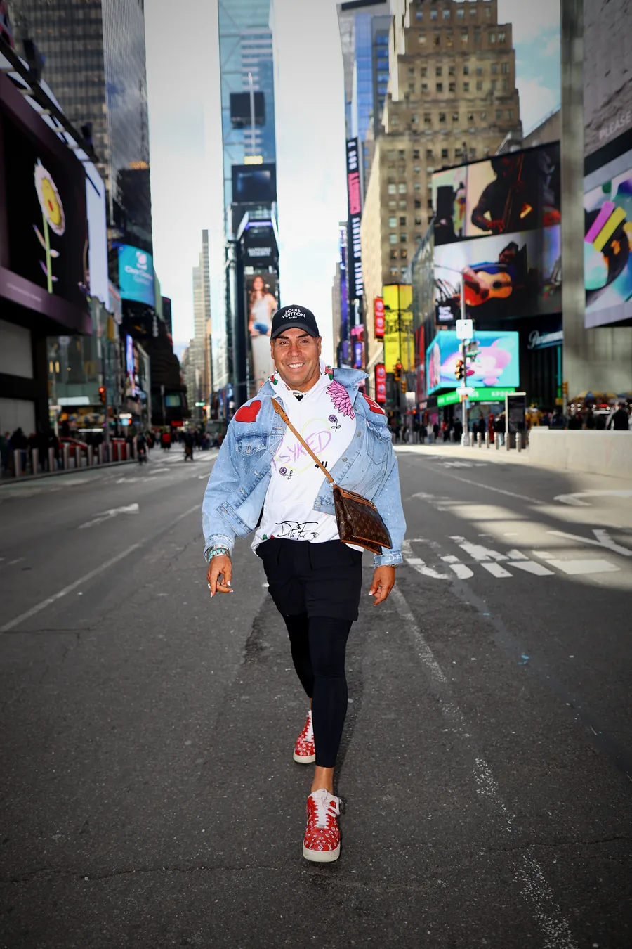 Dr. Rick Perea walking through Times Square in a denim jacket